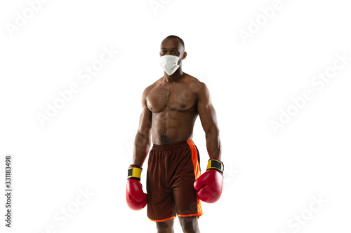 Beat off the virus. African-american boxer in protective mask, gloves. Prevention against pneumonia. Still active while quarantine. Chinese coronavirus treatment. Healthcare, medicine, sport concept. photo