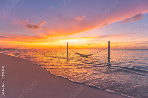 Fototapeta Naklejka Na Ścianę i Meble -  Beautiful landscape on sunset beach, orange evening as luxury travel background. Amazing sunset colors, soft waves on empty beach with swing or hammock. Summer landscape, tropical sunset on vacation