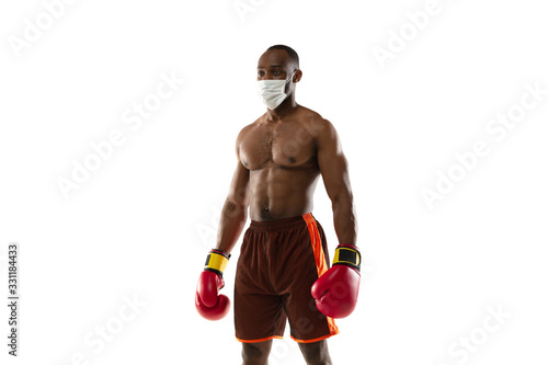 Beat off the virus. African-american boxer in protective mask, gloves. Prevention against pneumonia. Still active while quarantine. Chinese coronavirus treatment. Healthcare, medicine, sport concept. photo