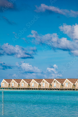 Water villas in the ocean with steps into turquoise lagoon. Exotic travel and summer vacation vertical banner design