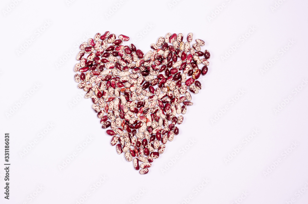 Dry purple beans for vegans in the form of a heart on a white background copy space