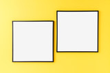 Two empty picture frames on yellow wall. Mockup with copyspace