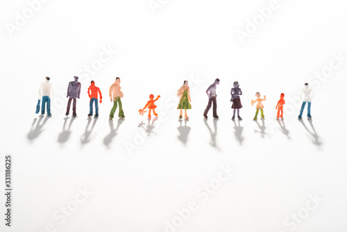 Close up view of row of people figures on white surface with shadow
