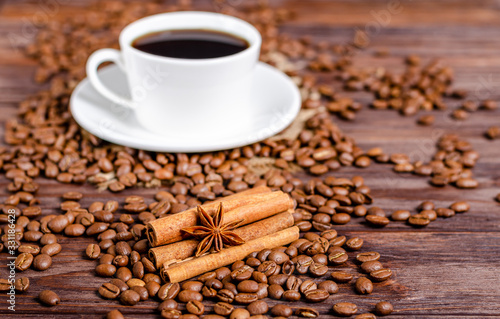 Anise star on cinnamon sticks with roasted arabica coffee beans on wooden background.