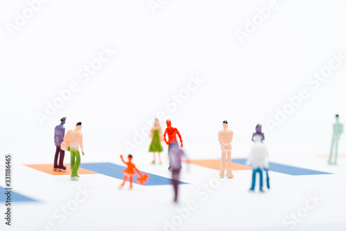 Selective focus of plastic people figures on surface with charts isolated on white, concept of equality