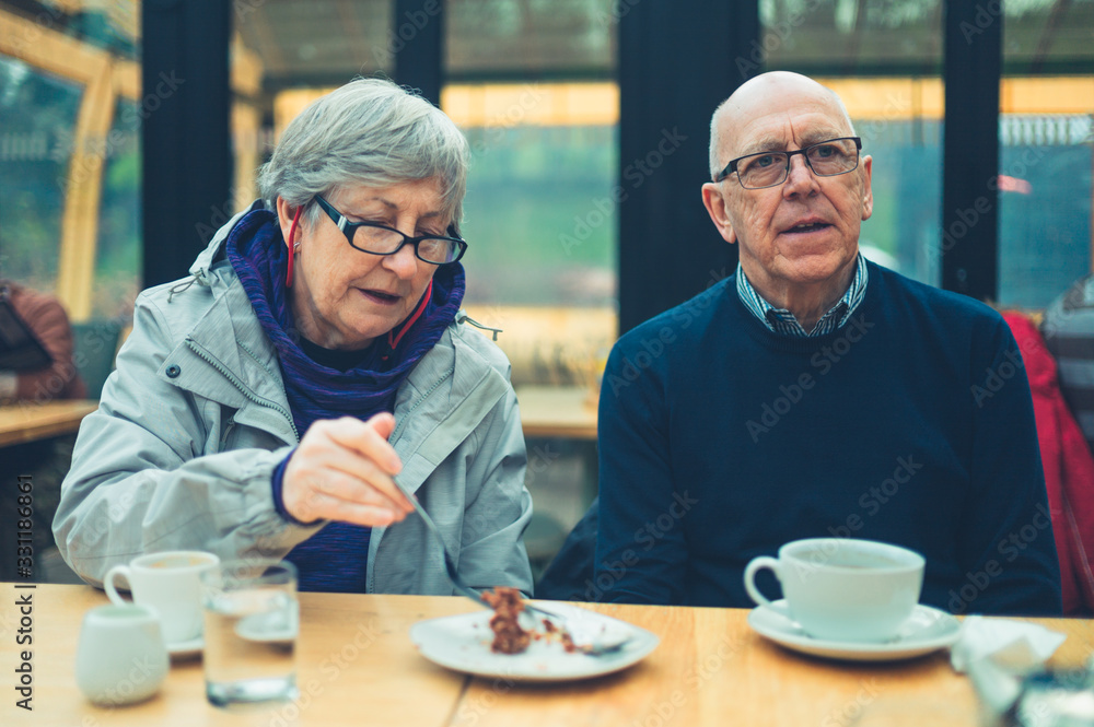 Mature couple drinking coffee and sharing cake in a cafe Mature couple drinking coffee and sharing cake in a cafe
