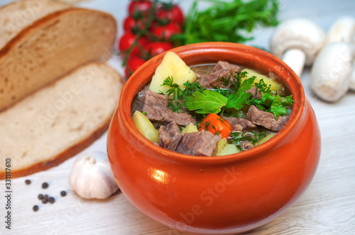 Roast in a pot with beef meat and potatoes on the table