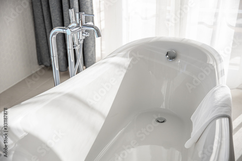 Bild auf Leinwand Bathtub in master bathroom in new luxury home, white tub, towel in soft sunlight