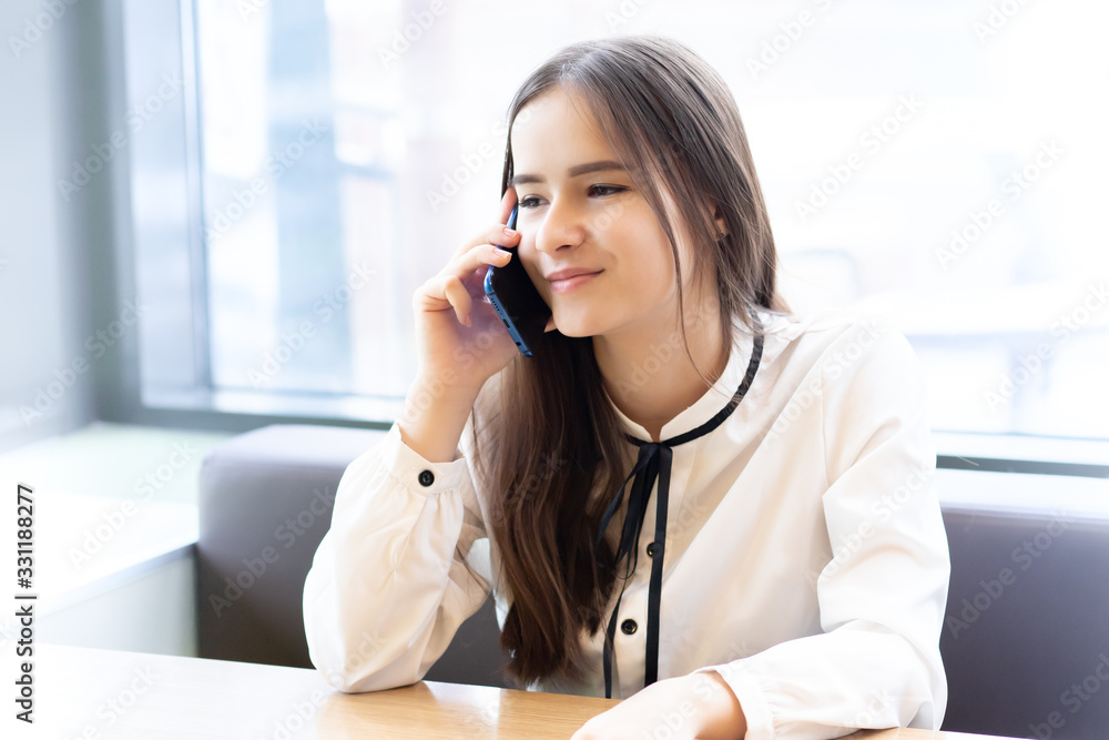 Student girl in a cafe with a smartphone, talking, smiling Student girl in a cafe with a smartphone, talking, smiling