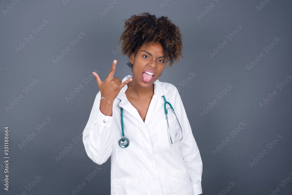 Portrait of a crazy doctor girl showing tongue horns up gesture, expressing excitement of being on concert of band. Portrait of a crazy doctor girl showing tongue horns up gesture, expressing excitement of being on concert of band.