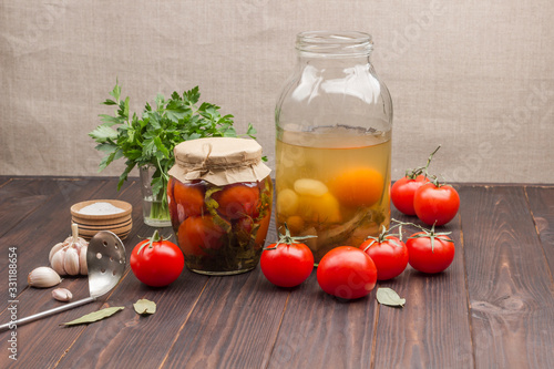 Glass jar of canned tomatoes, fresh tomatoes, green parsley, garlic .