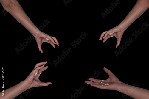 4 hands on a black background reaching for something in the center. The concept of ordering something, different things. earn a discount or item