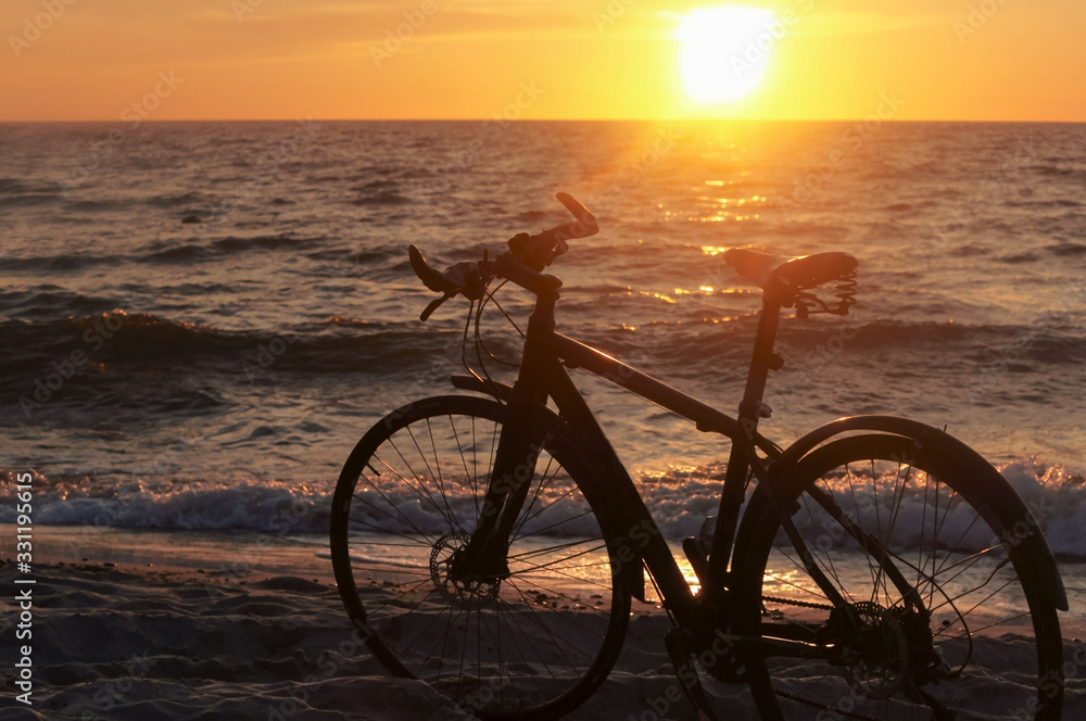 Fototapeta premium Cycling along the sea coast, Bicycle at sunset