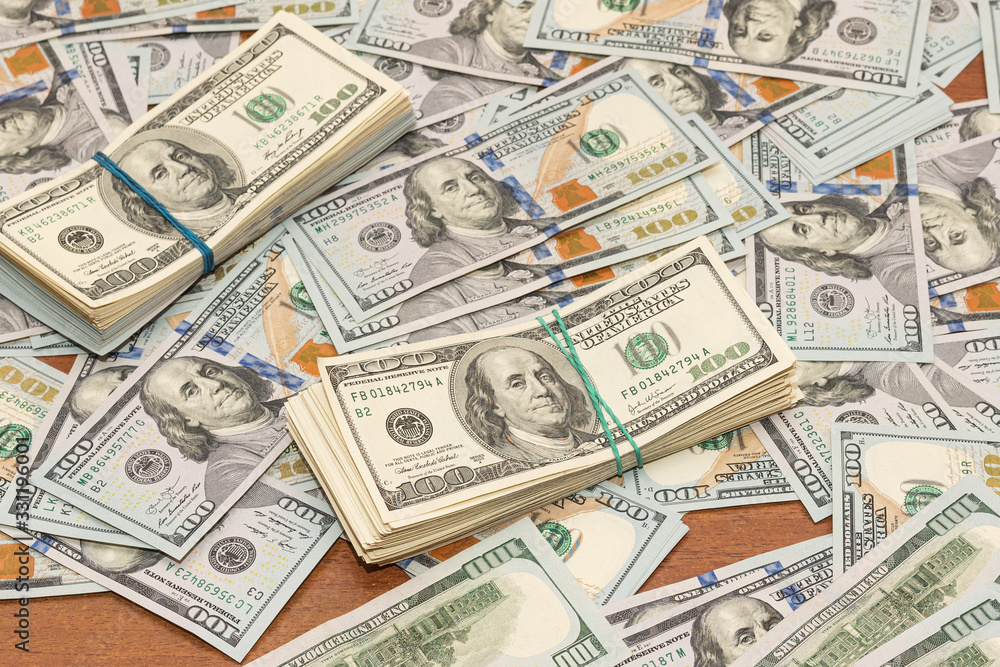 Many hundred dollar bills on wooden table background texture. bundles of money scattered on the office desk. wealth and income concept Many hundred dollar bills on wooden table background texture. bundles of money scattered on the office desk. wealth and income concept