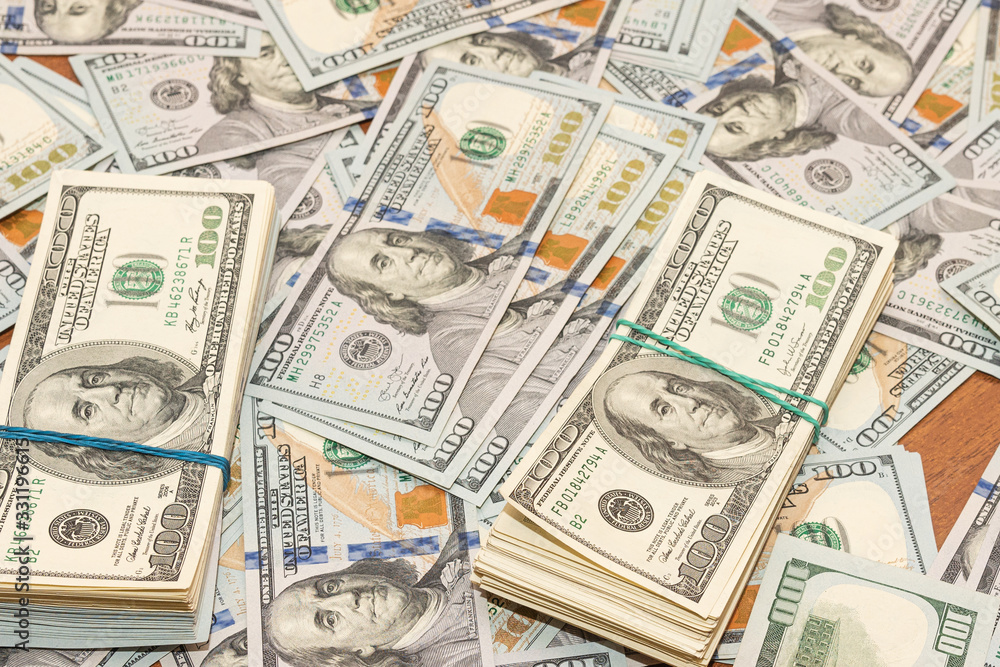 Many hundred dollar bills on wooden table background texture. bundles of money scattered on the office desk. wealth and income concept Many hundred dollar bills on wooden table background texture. bundles of money scattered on the office desk. wealth and income concept
