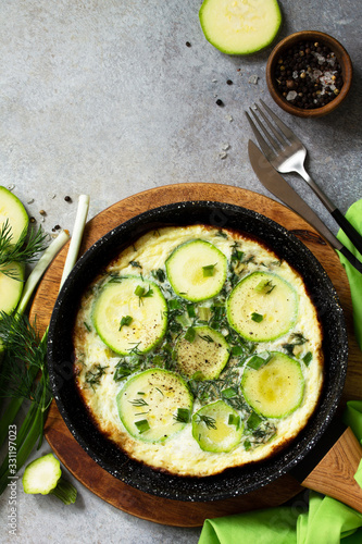 Breakfast. Summer omelet with zucchini and herbs on a stone or slate table. Top view flat lay. Copy space.