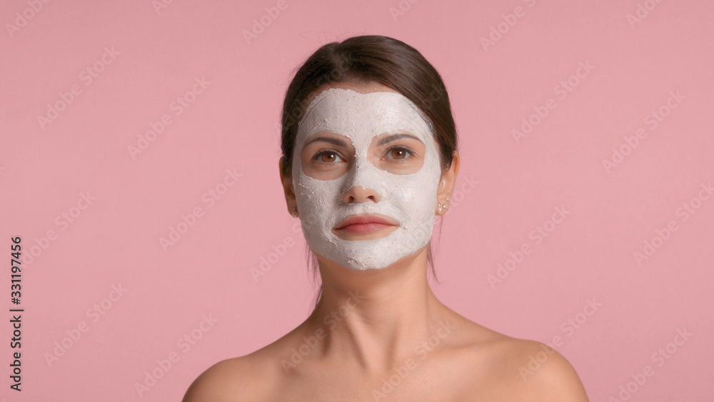 30s brunette woman with a facial clay mask on laughing and having fun making faces in studio on pink background 30s brunette woman with a facial clay mask on laughing and having fun making faces in studio on pink background