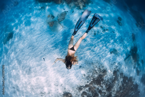 Woman freediver glides with fins over sandy sea bottom. Freediving and sun light in ocean © artifirsov