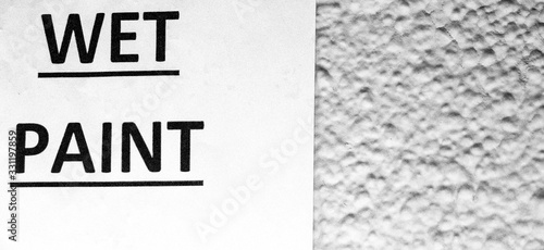Wet Paint sign  black and white monochrome sign against a rough textured wall with room for text copy space. 