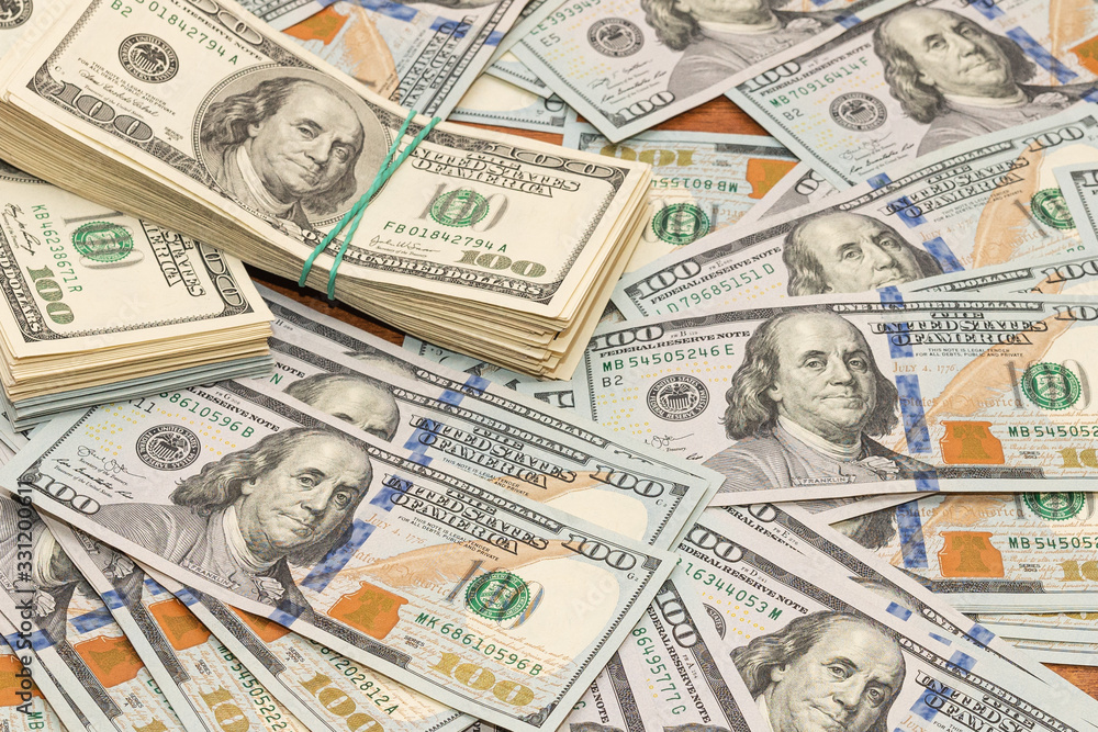 Many hundred dollar bills on wooden table background texture. bundles of money scattered on the office desk. wealth and income concept Many hundred dollar bills on wooden table background texture. bundles of money scattered on the office desk. wealth and income concept