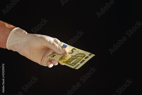 Hand in latex glove holding paper money cash