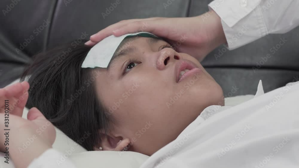 Sick woman lying on sofa with cool fever gel on forehead Sick woman lying on sofa with cool fever gel on forehead