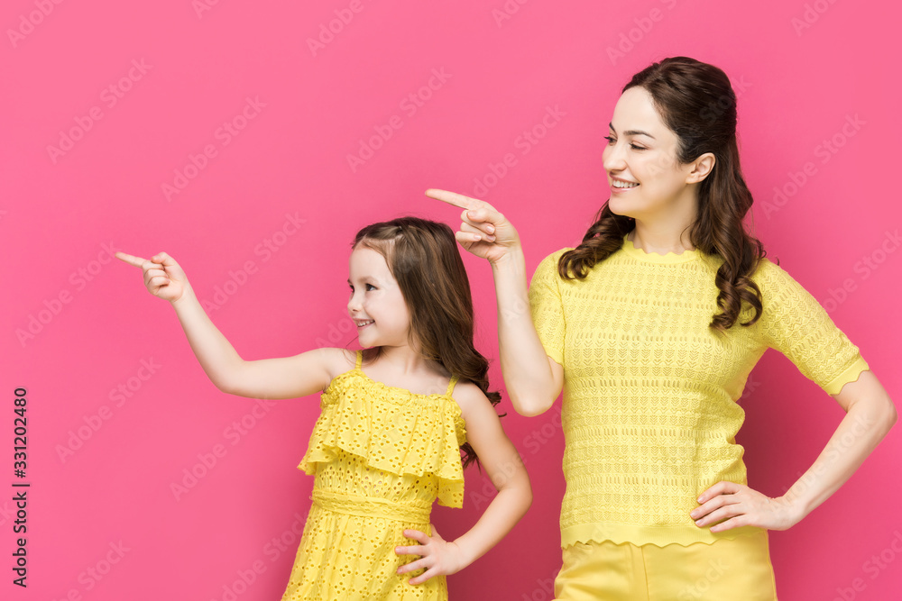 happy mother and kid pointing with fingers isolated on pink happy mother and kid pointing with fingers isolated on pink