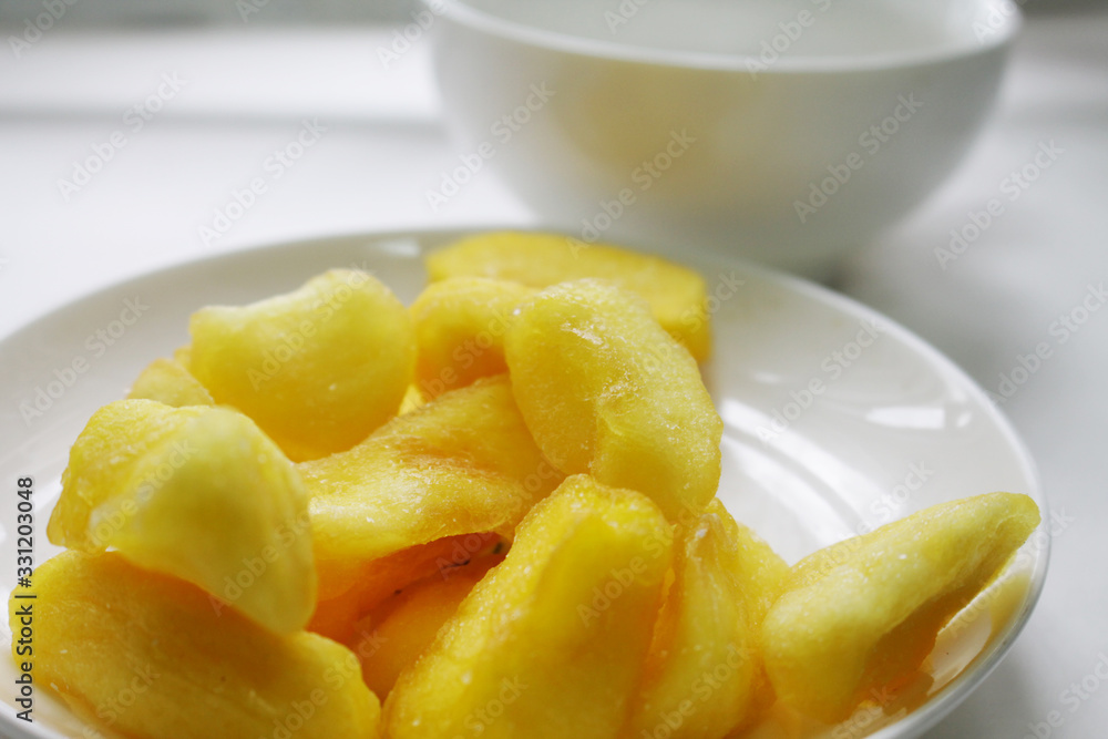 Dried yellow fruits on a plate and a white tea cup. Dried yellow fruits on a plate and a white tea cup.