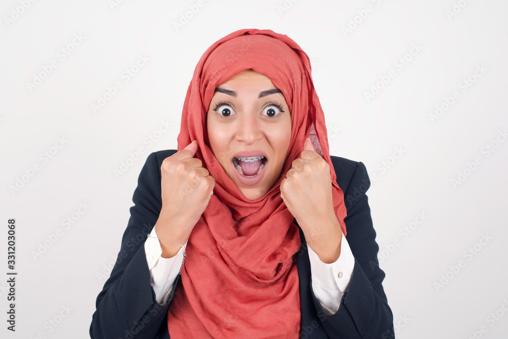 Caucasian young woman rejoicing her success and victory clenching her fists with joy.Lucky woman with hat being happy to achieve her aim and goals.Positive emotions, feelings. Caucasian young woman rejoicing her success and victory clenching her fists with joy.Lucky woman with hat being happy to achieve her aim and goals.Positive emotions, feelings.