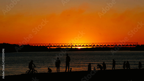 silhouette of people on pier at sunset