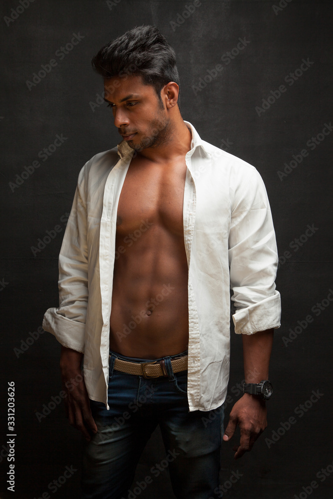Dark tanned body builder wearing white shirt showing sculpted body