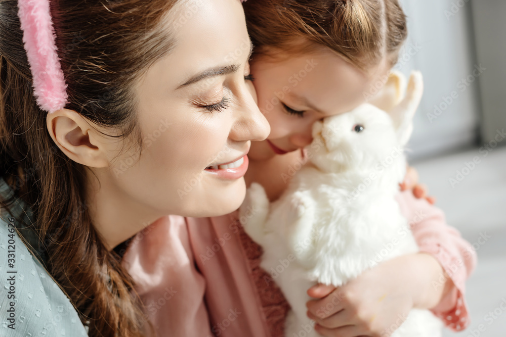 selective focus of happy mother near cute kid with toy rabbit selective focus of happy mother near cute kid with toy rabbit