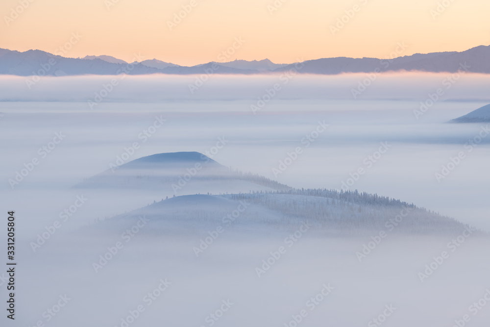 winter landscape with mountains and fog. Beautiful sunrise over the mountains in foggy morning. Colorful winter landscape in mountains