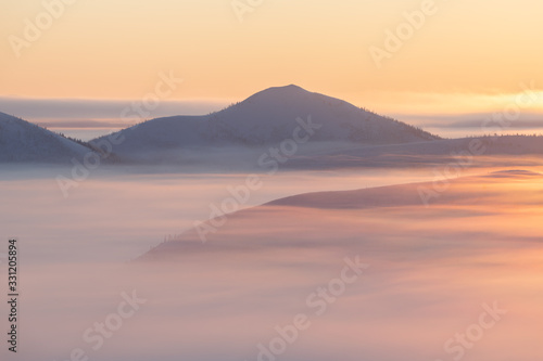 Beautiful sunrise over the mountains in foggy morning. Colorful winter landscape in mountains