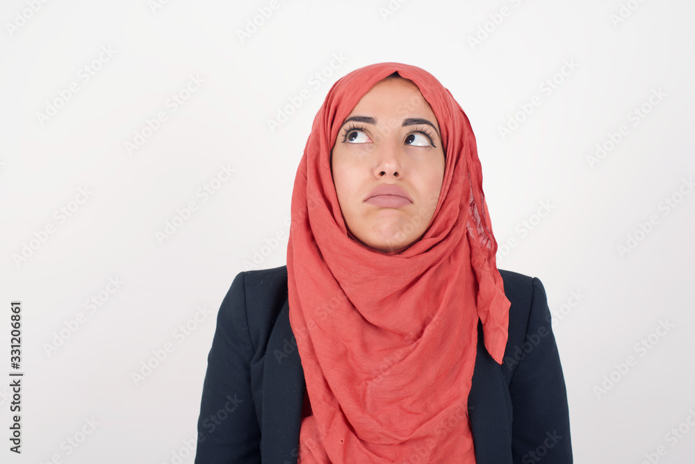 Gloomy, bored girl frowns face looking up, being upset with so much talking hands down, feels tired and wants to leave. Angry sullen woman standing indoors. Gloomy, bored girl frowns face looking up, being upset with so much talking hands down, feels tired and wants to leave. Angry sullen woman standing indoors.