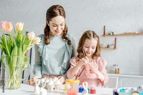 Photography selective focus of child and mother near tulips and easter eggs