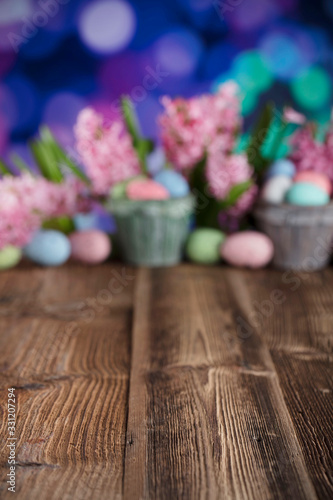Easter background. Rustic wooden table. Tulips and spring flowers. Easter eggs. Pastel colors bokeh. 