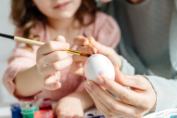 Cropped view of mother and daughter painting easter egg