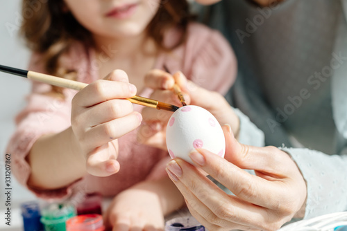 Obraz na plátne Cropped view of mother and daughter painting easter egg