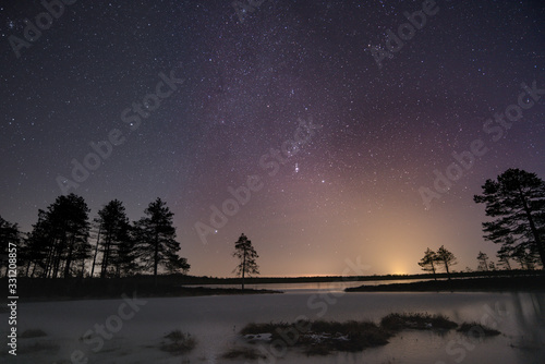 Vivid night sky over frozen lake and swamp landscape
