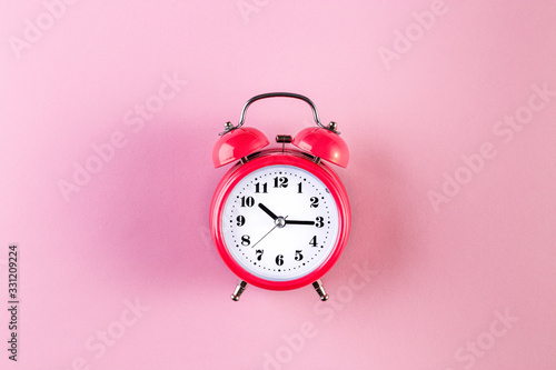 Red vintage alarm clock on light pink color background. Alarm clock with place for text. Time management concept, business planning
