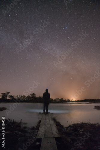 Figure on path in bog under starry night sky and Milky Way