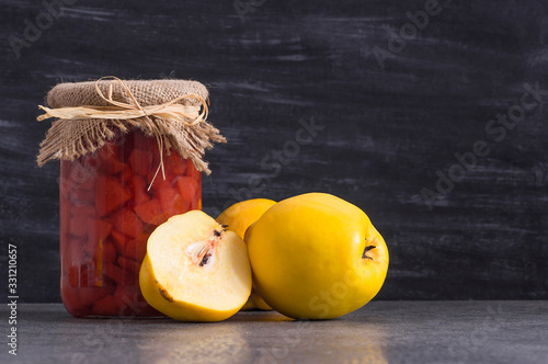 quince jam in glass jar with ripe fresh quinces on rustic table, fruit jam concept for breakfast photo