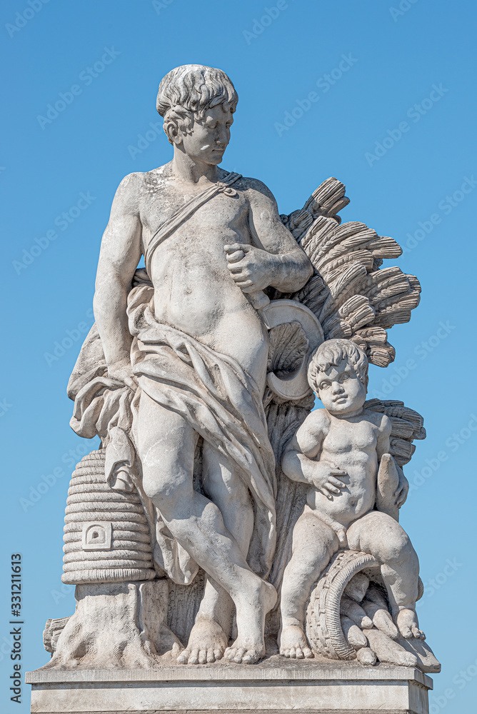 Elderly and young – old sculpture of farmer and his scholar on Zoll Bridge in Magdeburg downtown at blue sky background, Germany, details, closeup