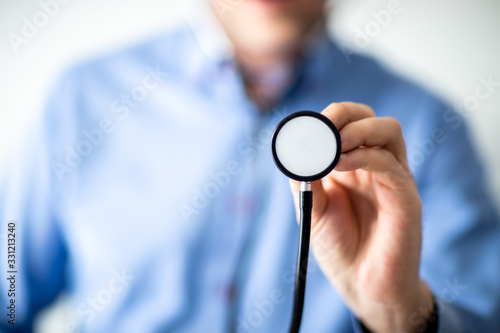 Lekarz w niebieskiej koszuli trzymający stetoskop w dłoni