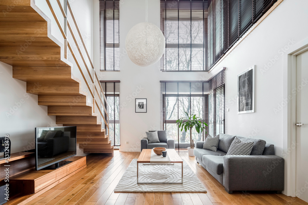 Spacious living room with wooden stairs - obrazy, fototapety, plakaty 
