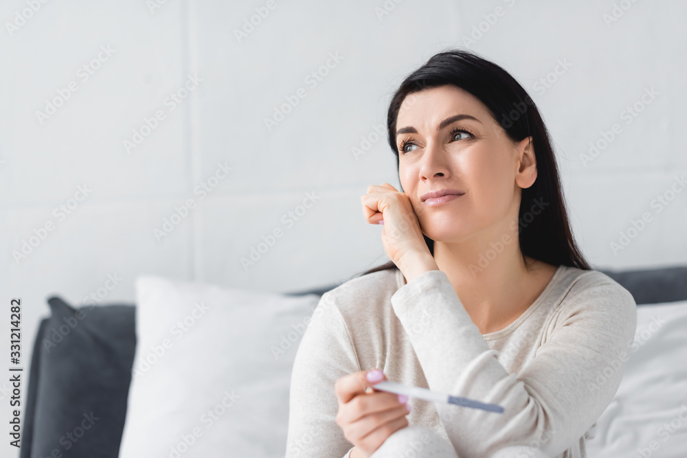 upset woman crying while holding pregnancy test with negative result upset woman crying while holding pregnancy test with negative result