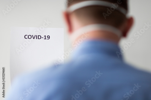 mężczyzna w masce ochronnej spoglądający w napis COVID-19