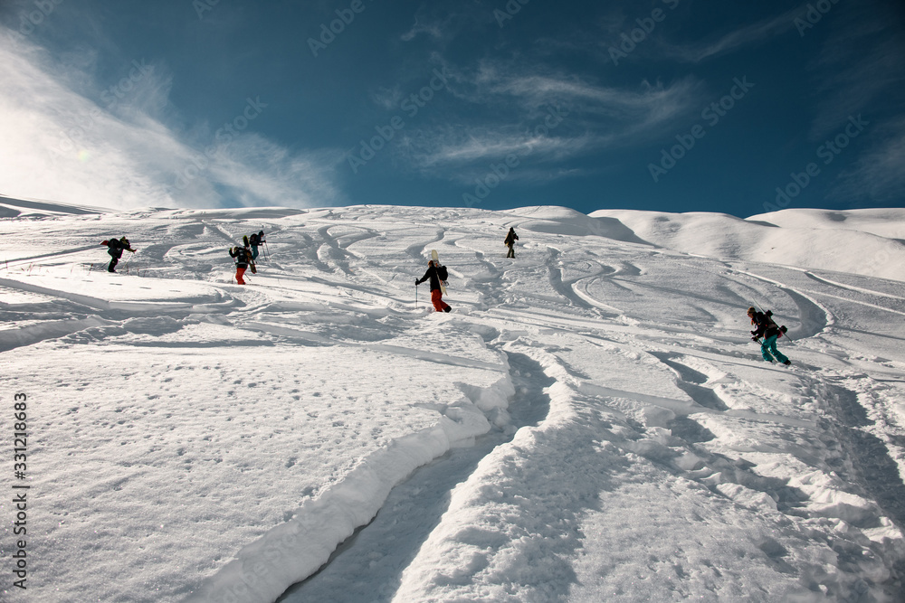 Group of men and women with ski equipment climb the mountain to make freeride.