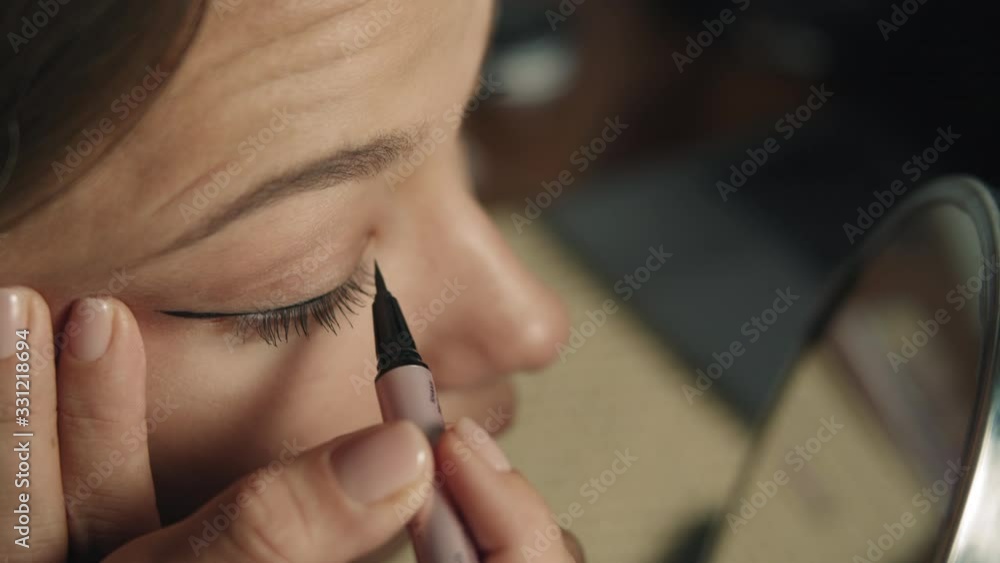 Makeup artist applying eyeliner to waterline by using eyeliner brush for making perfect makeup before charming beautiful model do her work. Attractive beautiful girl has perfect face, beautiful eyes Makeup artist applying eyeliner to waterline by using eyeliner brush for making perfect makeup before charming beautiful model do her work. Attractive beautiful girl has perfect face, beautiful eyes